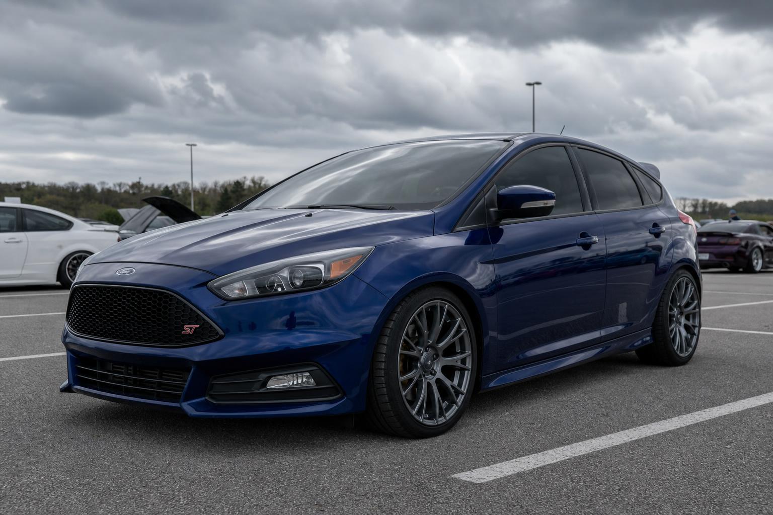 Dark blue 2016 Ford Focus ST slightly lowered with tinted windows at a car meet